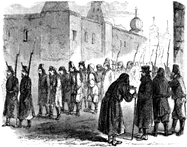 Prisoners shackled in pairs are escorted through the street by guards