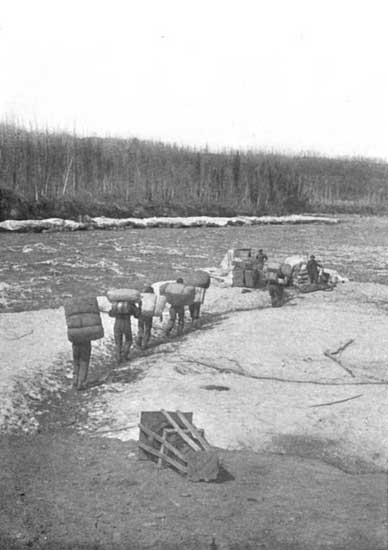 Indian voyageurs "packing" over long portage, each packet containing from fifty to one hundred pounds.