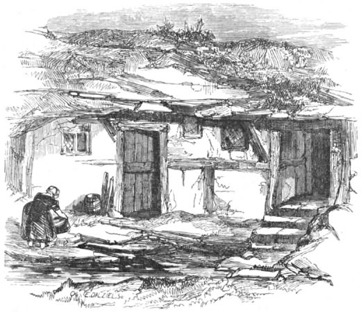 A woman works outside one of the simple buildings