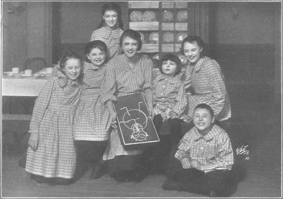 Judy with a laughing group of orphans, showing one of her drawings