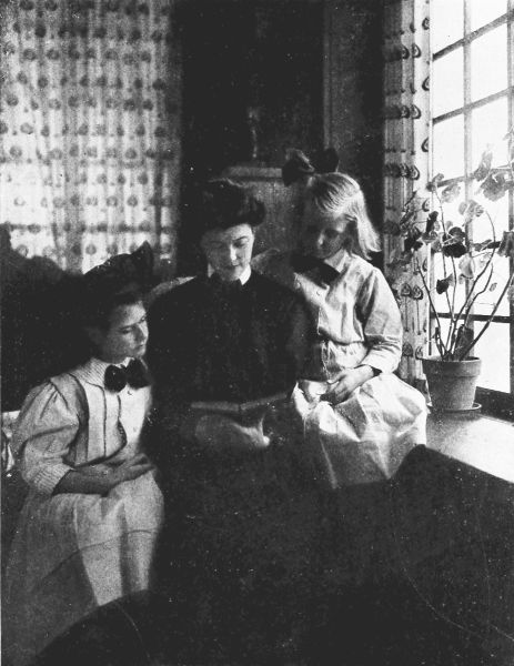 Phtotograph of of two girls listening to a woman read a book