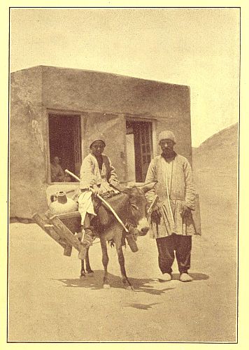 photograph of boy on donkey and man standing by
