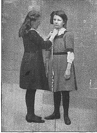 one girl measuring another at neck