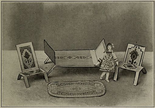 Photograph: two chairs, a bed, a rug and a paper doll