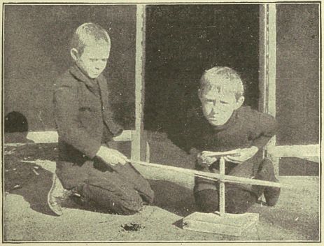 photograph of two boyx making fire with drill