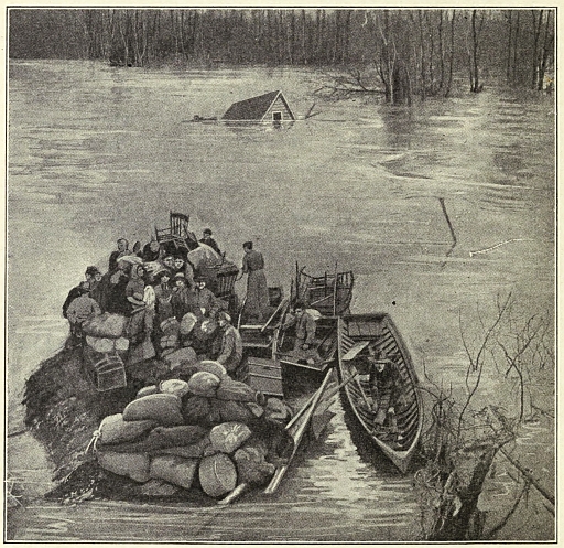 people on overflowing raft full of bundles; house roof just sticking up out of water