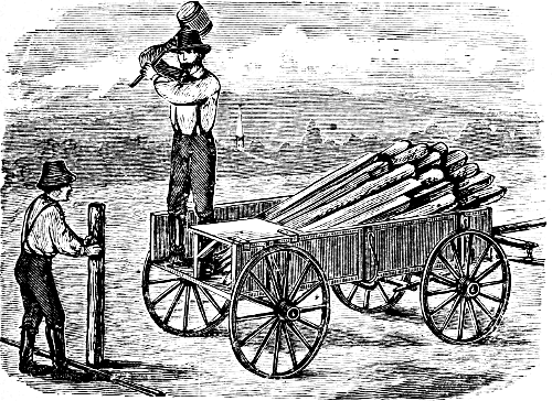 man on wagon pounding in a post