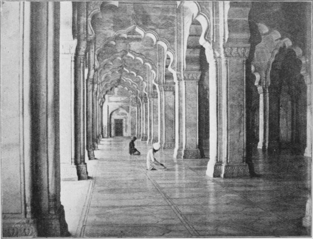 Image of two people praying in large mosque.