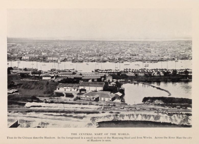 THE CENTRAL MART OF THE WORLD. Thus do the Chinese describe Hankow.  In the foreground is a small section of the Hanyang Steel and Iron Works. Across the River Han the city of Hankow is seen.