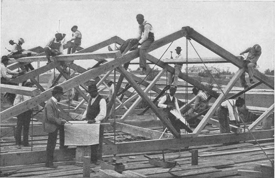 STUDENTS FRAMING THE ROOF OF A LARGE BUILDING