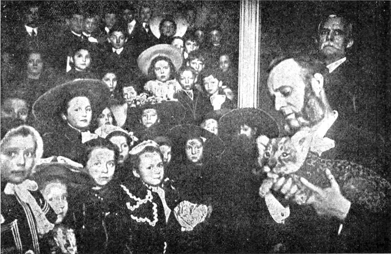 Photograph of Woolston holding a baby lion in front of a crowd of people