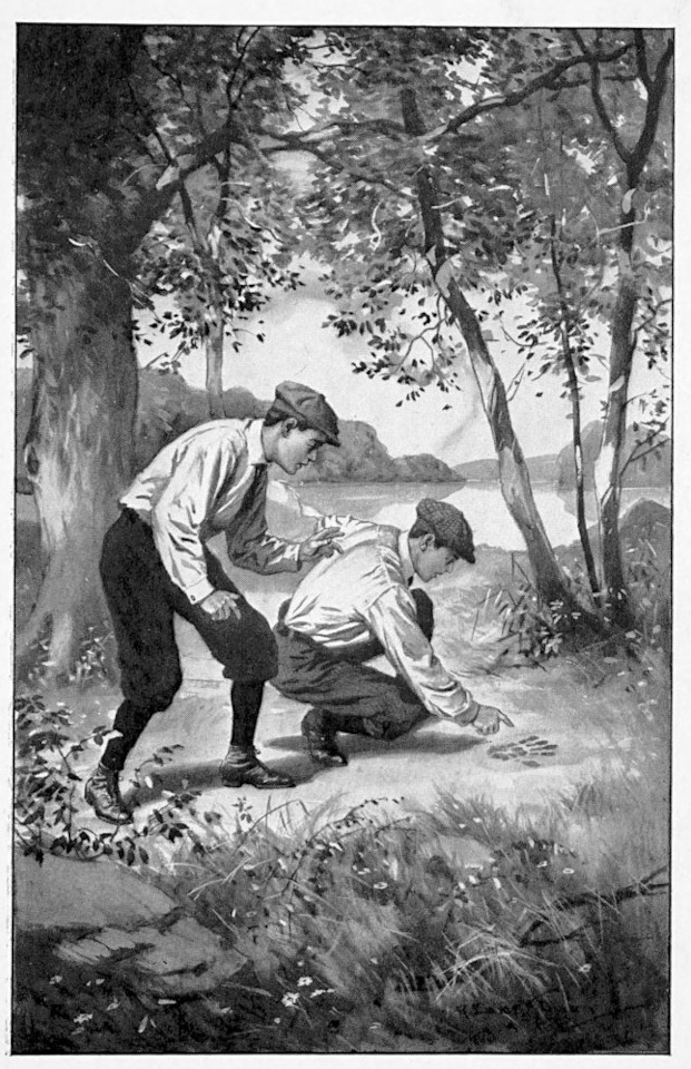 Two boys crouched looking at a
footprint.