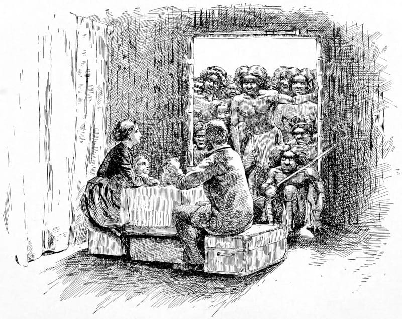 Two people seated with an audience watching through a doorway.