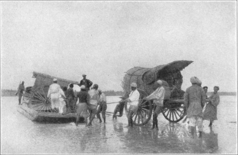 A cart being pulled through shallow water, with a second cart behind being unloaded from a wooden ferry.