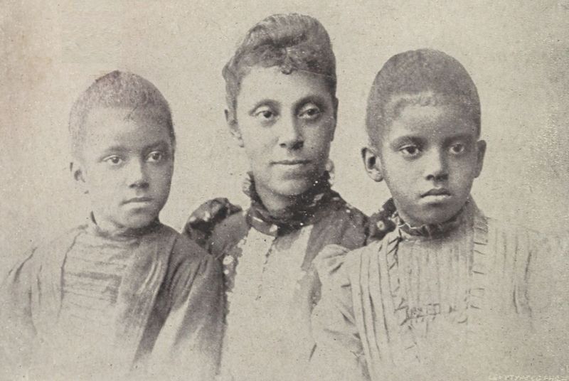 The illustration shows
Mrs. N. F. Mossell (Gertrude Bustill Mossell) with her daughters, Florence
and Mary, standing on either side of her. Mossell’s hair is styled in an
updo, while her daughters have short hair. All three wear Victorian dresses
decorated with pleats, ruffles, and buttons.